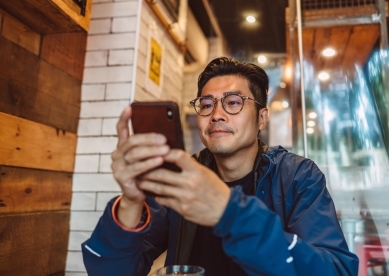 Young Asian man making order from the digital menu on smartphone in restaurant